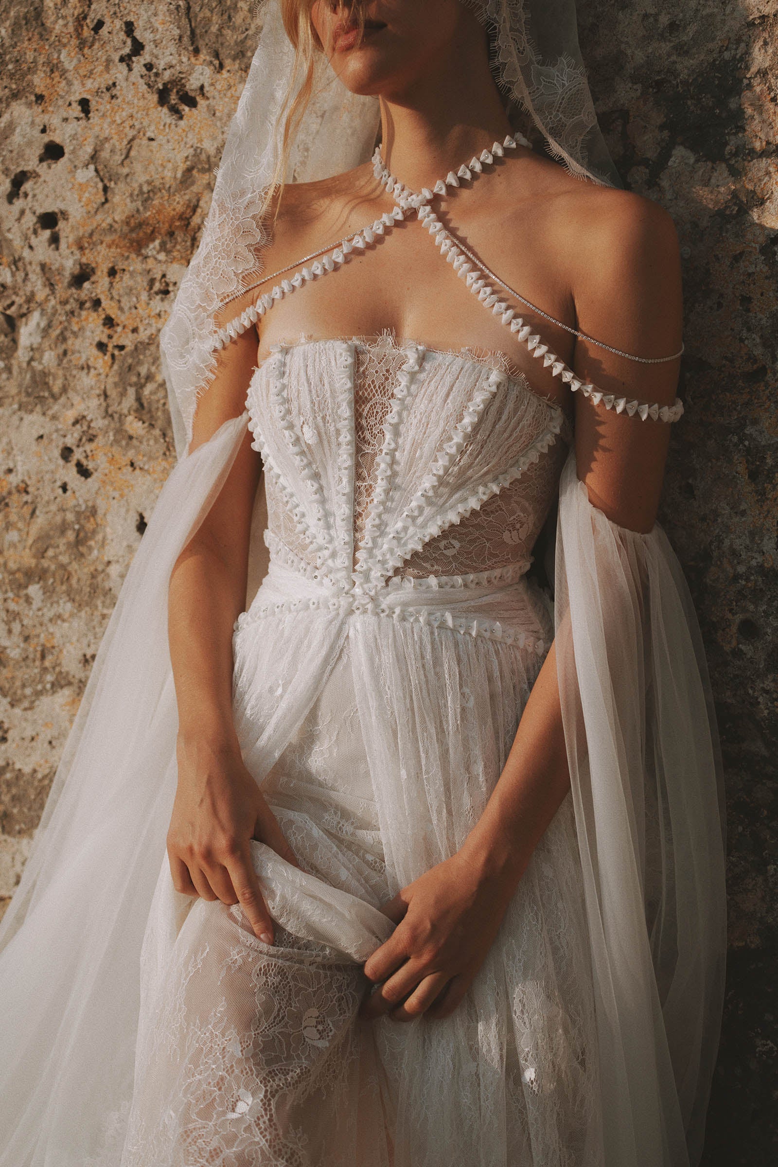 Intricate detailing of a lace wedding dress and accessories against a stone wall_XS_