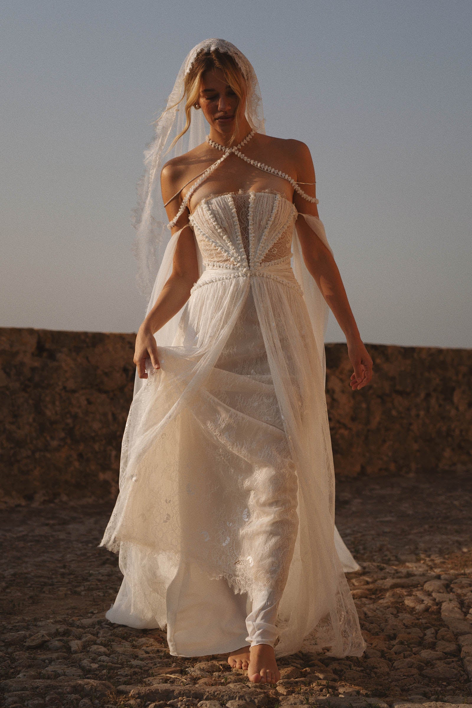 Woman in a lace wedding dress standing on a rocky landscape_XS_