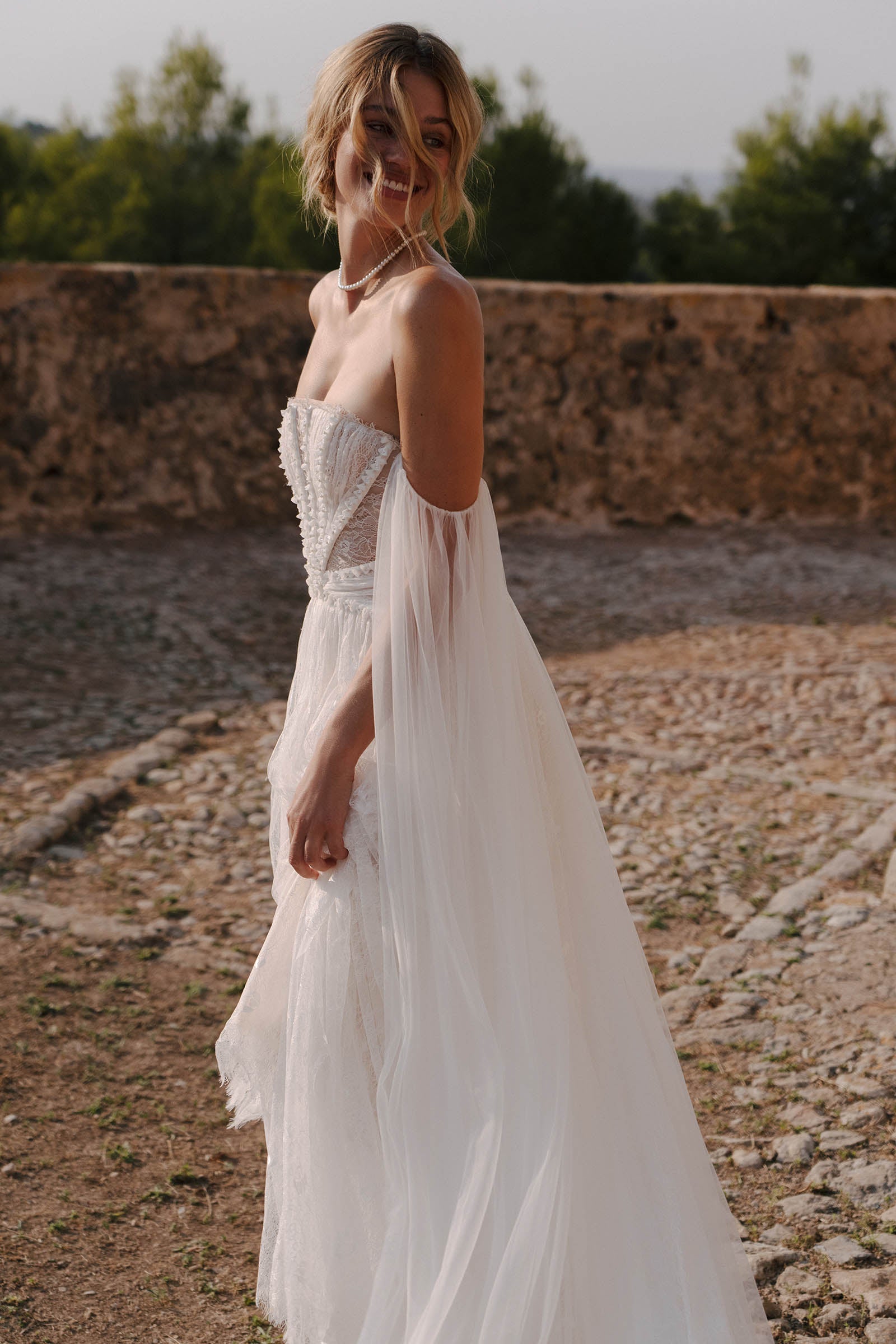 Woman in a lace wedding dress standing outdoors_XS_