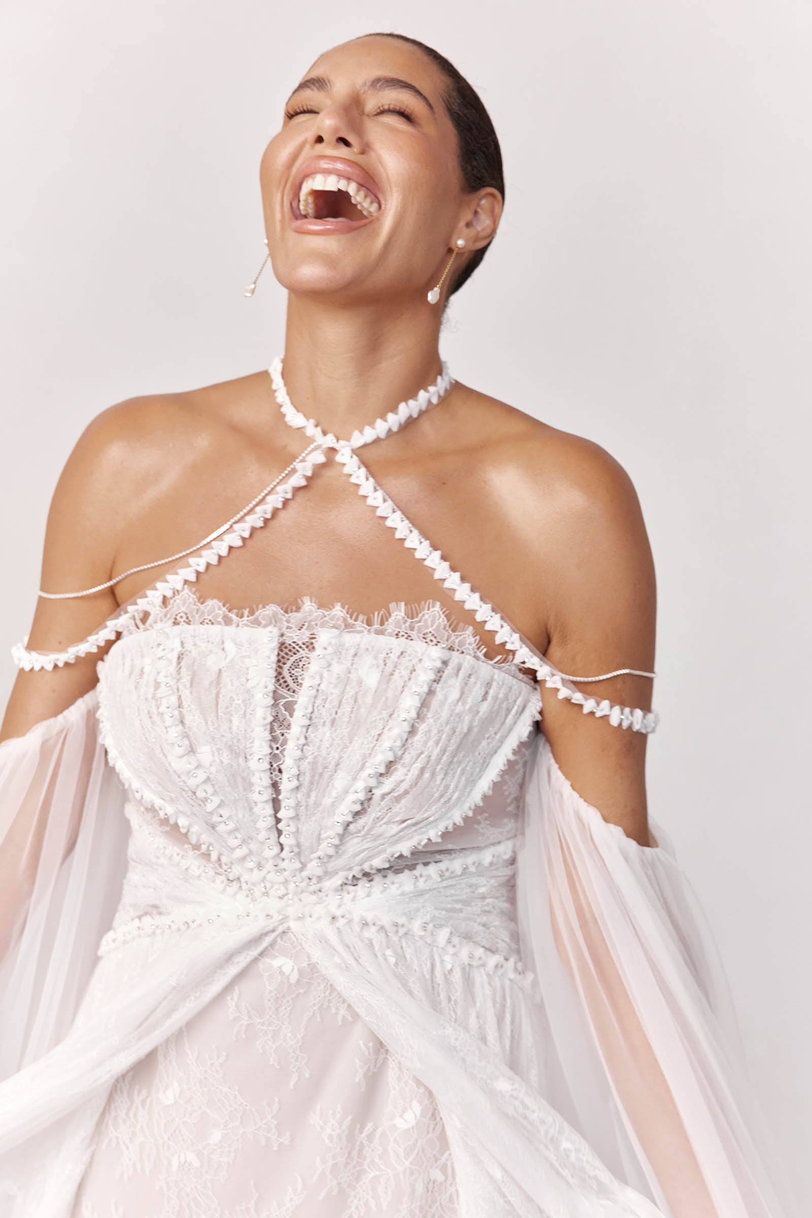 Woman wearing a lace wedding dress with a sheer sleeves laughing_L_