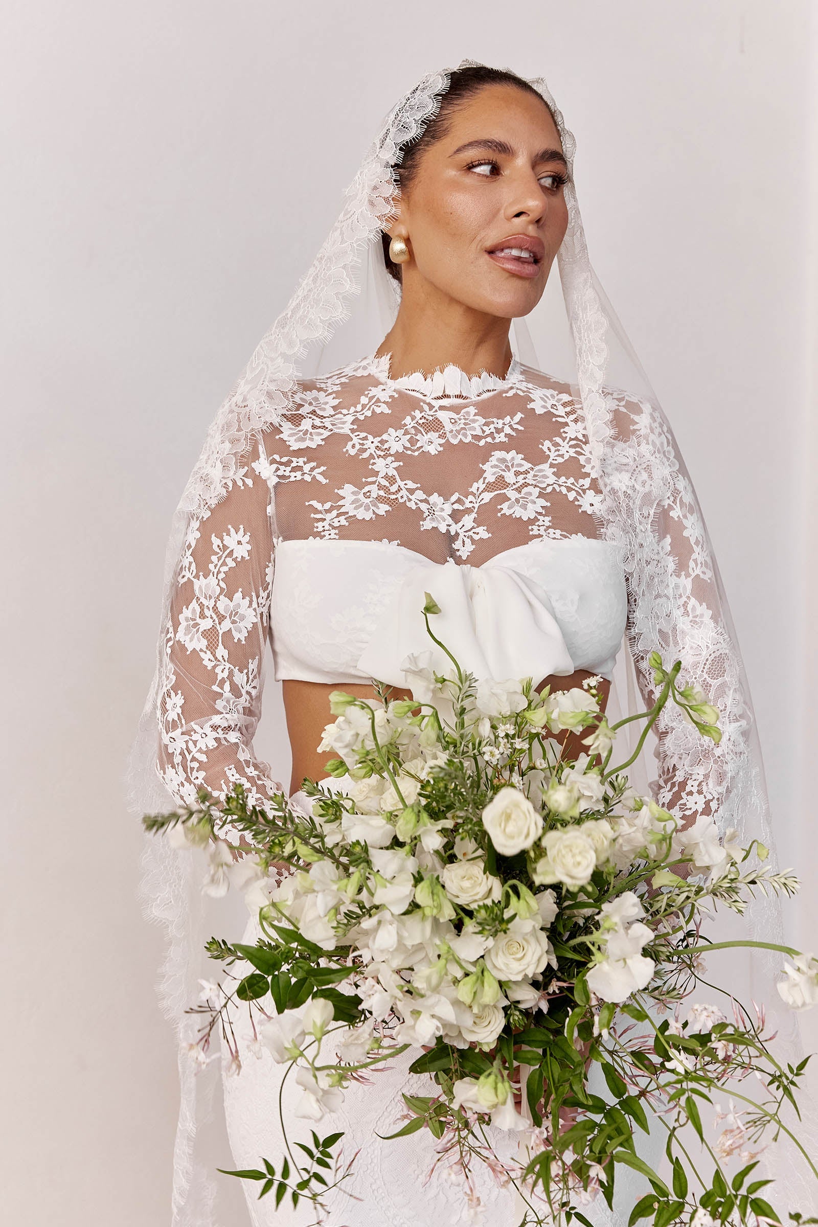 Woman in a long sleeve lace wedding dress holding a bouquet_L_