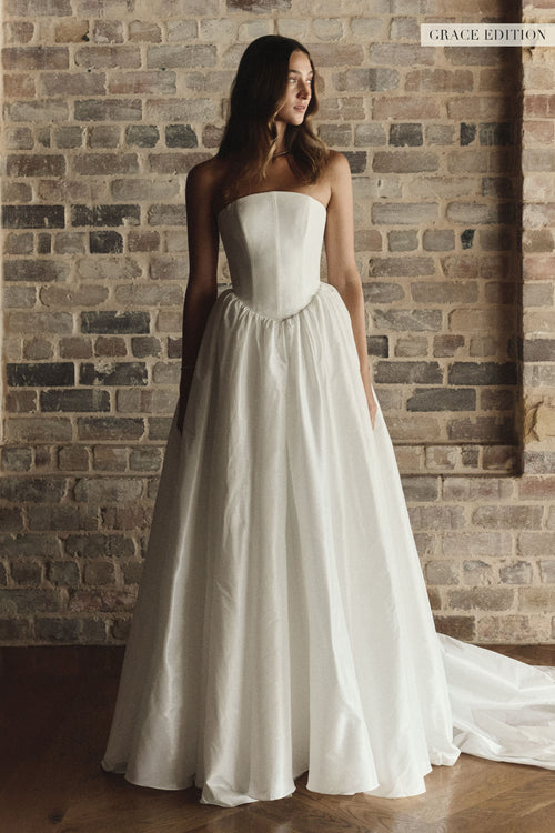 A woman wearing a strapless white wedding gown with a structured bodice and full skirt