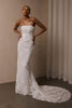 A woman wearing a strapless white lace wedding gown with a long train