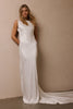A woman modeling a sleeveless white satin floor-length gown with a high neckline and a long train, standing against a plain beige wall_XS_
