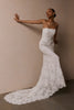 A woman wearing a strapless white lace wedding gown with a long train