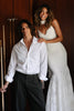 Man in a white shirt and black pants standing next to a woman in a white wedding dress with a white shawl