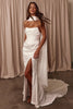 Woman wearing a white strapless dress with a high slit and white shawl.