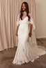 Woman wearing a white lace wedding dress with a sheer overlay cape