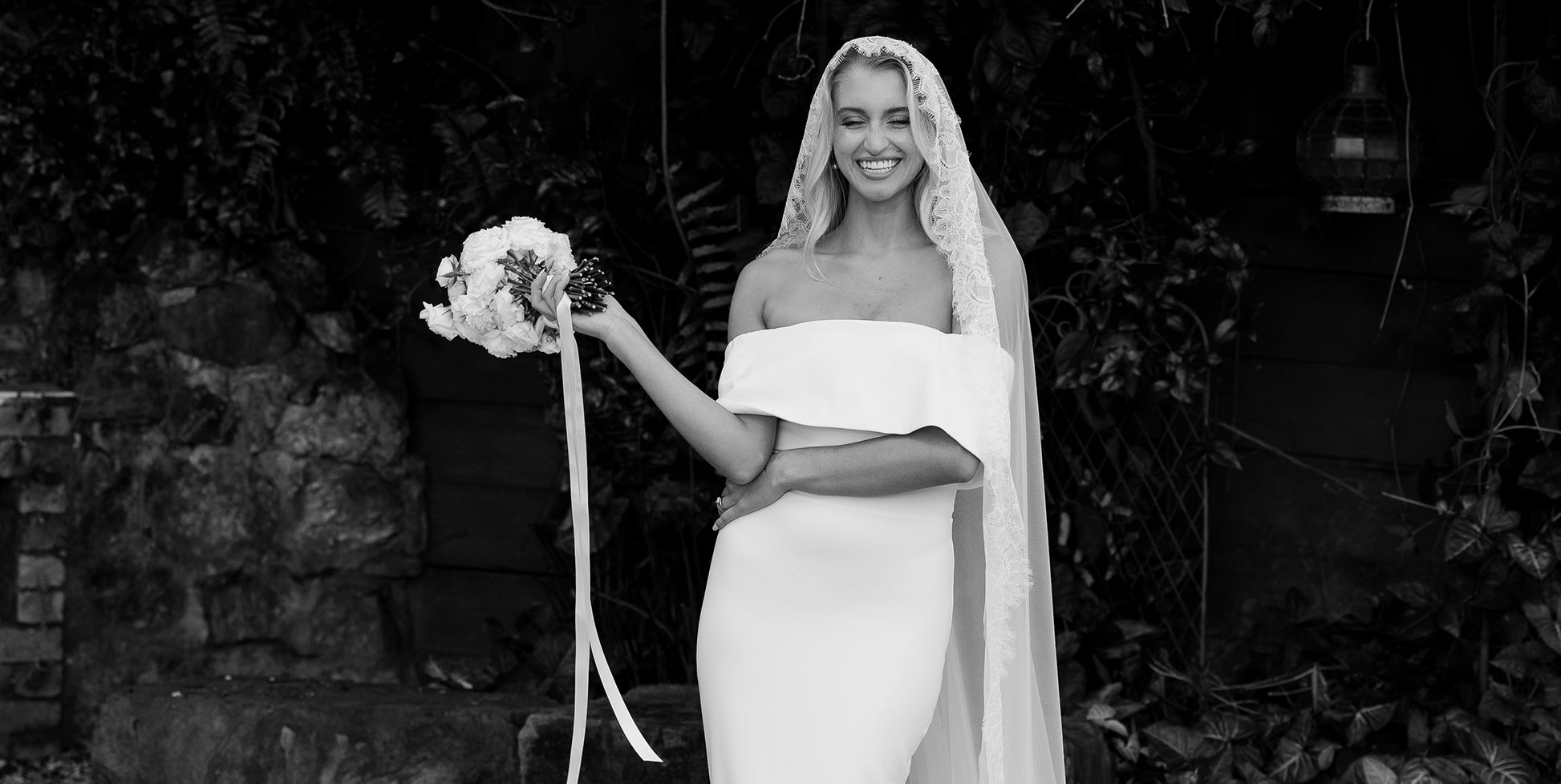 A bride wearing an off the shoulder wedding dress and veil.