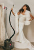 Woman wearing a wedding dress holding a garment steamer