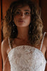 Woman wearing a white lace dress with long pearl earrings