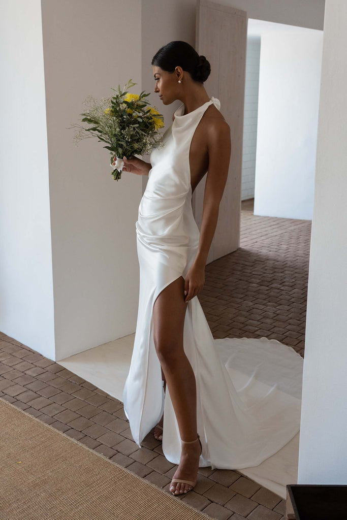 Bride wearing the Goldie gown and holding yellow floral arrangement