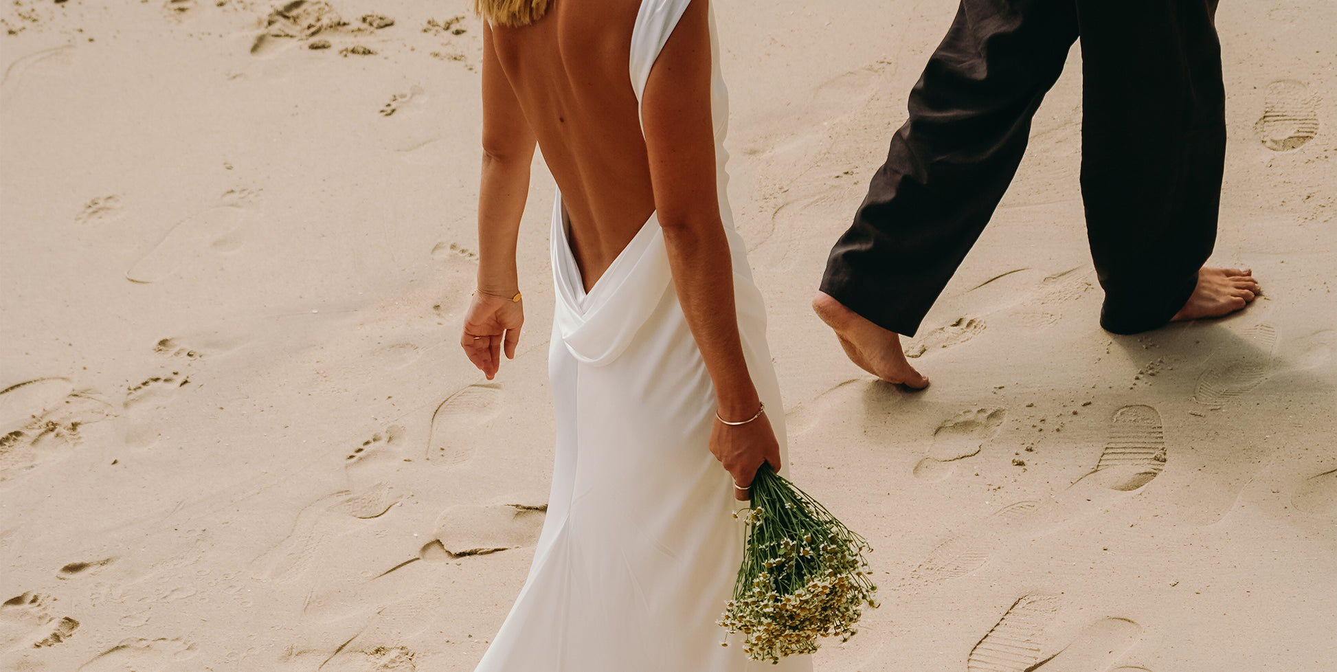A bride and groom walking along the beach