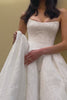 Woman wearing a lace basque waist wedding dress adjusting the skirt