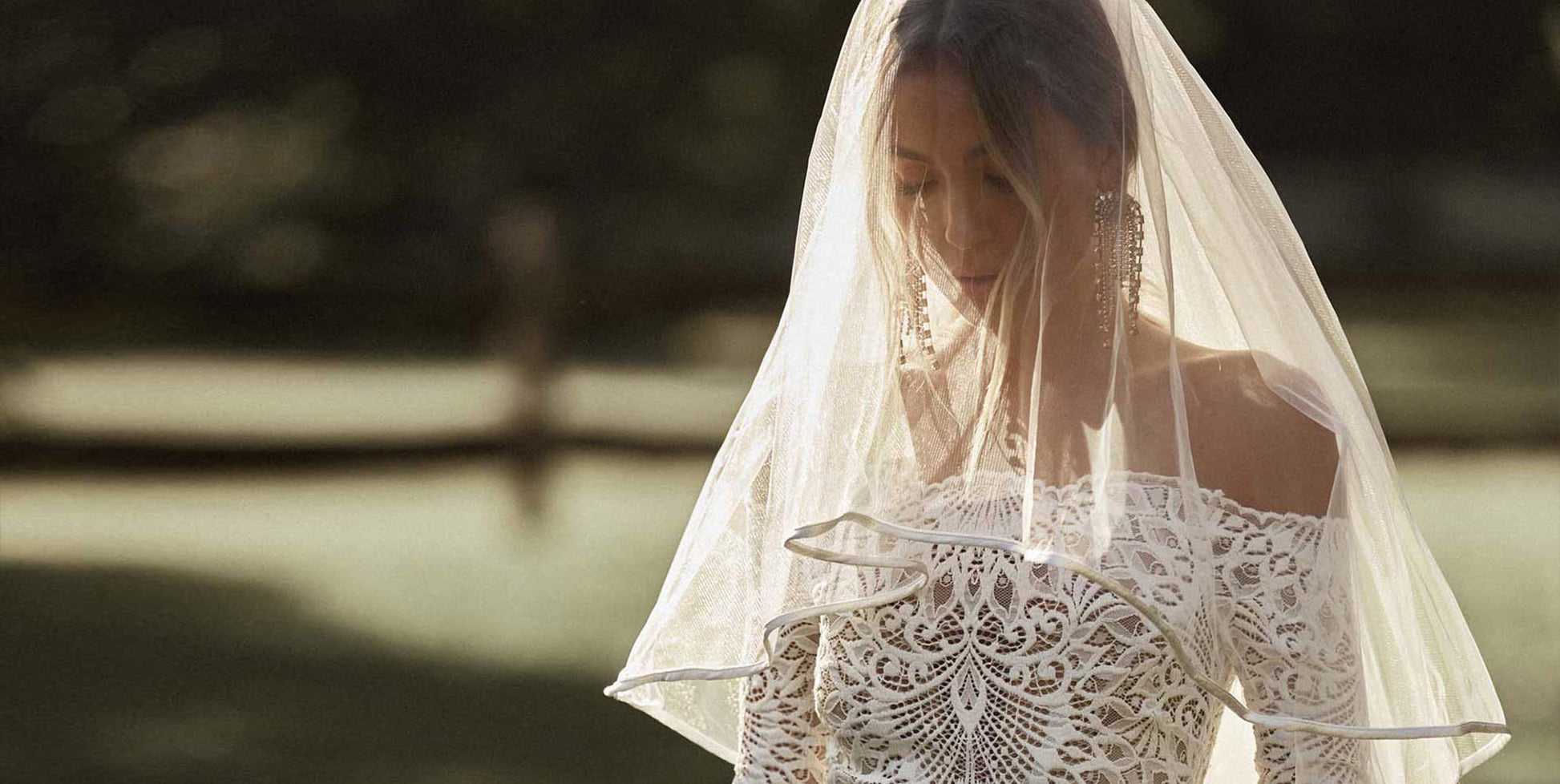 Woman wearing a blusher veil and lace wedding dress.
