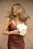 Model twirling in Classic Slip Dress in Copper with white wedding bouquet